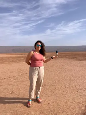a woman standing in the desert with a kite at Sahara Sunset Camp M'hamid in Mhamid