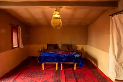 a room with a bed and a table in it at Sahara Sunset Camp M'hamid in Mhamid