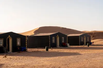 a group of black tents in the desert at Sahara Sunset Camp M'hamid in Mhamid