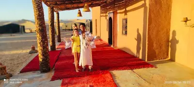two women and a girl standing on a red carpet at Sahara Sunset Camp M'hamid in Mhamid
