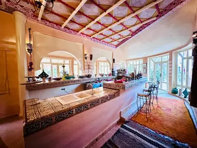 a kitchen with a sink and a counter with chairs at Ksar Jenna in Nkob