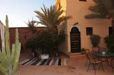 a patio with a table and chairs and plants at Ksar Jenna in Nkob