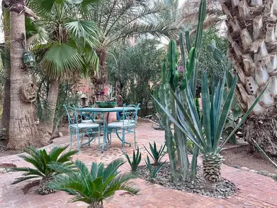 a patio with a table and chairs and palm trees at Ksar Jenna in Nkob