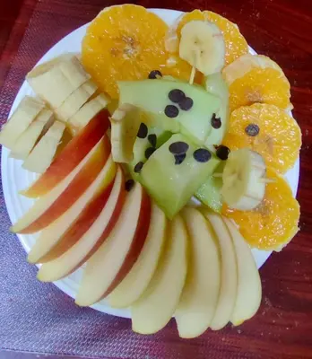 a plate of fruit with apples bananas oranges and other fruits at Riad Le Petit Patrimoine De Fés in Fès