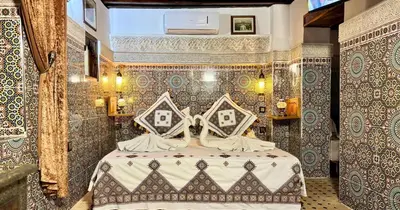 a bedroom with a bed in a room with tiled walls at Riad Le Petit Patrimoine De Fés in Fès