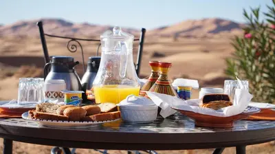 a table with bread and orange juice and drinks at Sleeping in a Luxury tent in Merzouga desert in Merdani