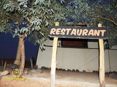 a sign for a restaurant in front of a building at Sleeping in a Luxury tent in Merzouga desert in Merdani