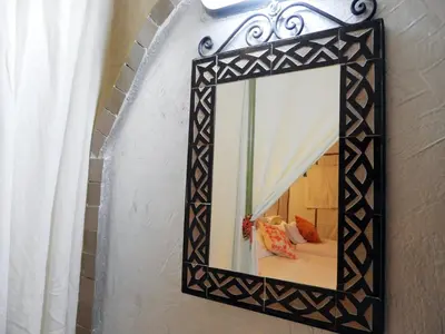 a mirror with a black frame hanging on a wall at Sleeping in a Luxury tent in Merzouga desert in Merdani