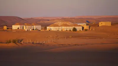 a group of houses in a desert with mountains in the background at Sleeping in a Luxury tent in Merzouga desert in Merdani