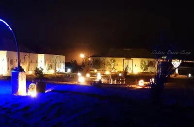 a couple of buildings at night with lights at Sleeping in a Luxury tent in Merzouga desert in Merdani
