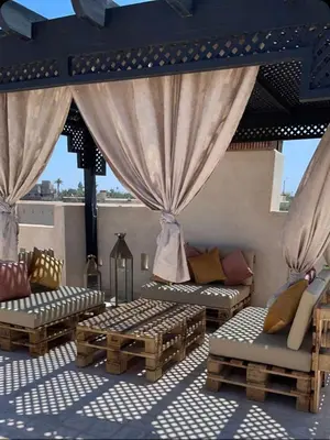 a patio with couches and chairs on a roof at La Rose des Sables in Marrakech