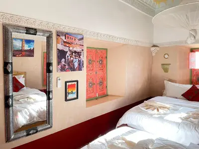 a bedroom with two beds and a mirror at Riad Dades Birds in Boumalne
