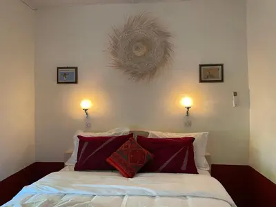 a bedroom with a bed with two lamps on the wall at Riad Dades Birds in Boumalne