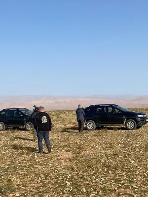 two people standing in a field with two cars at Riad Dades Birds in Boumalne