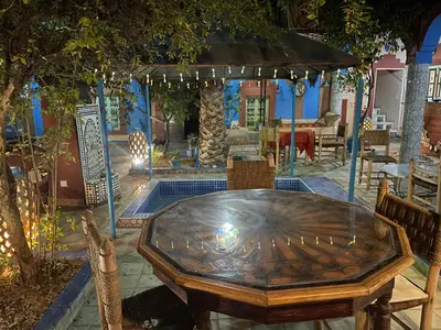 a table and chairs in a patio with a pool at Riad Dades Birds in Boumalne