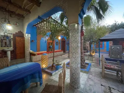 a room with blue walls and a table and trees at Riad Dades Birds in Boumalne