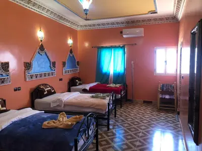 a bedroom with four beds in a room with orange walls at Dar fatima merzouga in Merzouga
