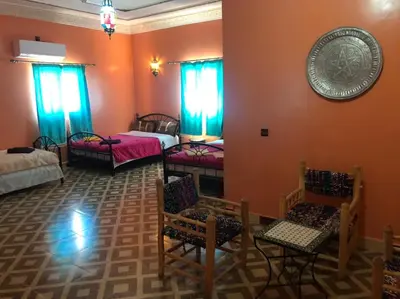 a room with several beds and chairs in it at Dar fatima merzouga in Merzouga