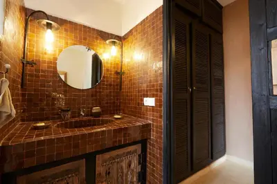 a brown tiled bathroom with a sink and a mirror at Kasbah Flilou in Aït Ougliff
