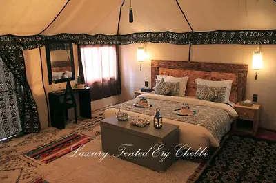 a bedroom with a large bed and a table in it at Luxury Tented Erg Chebbi in Merzouga