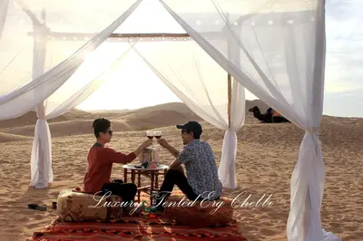 two men sitting at a table in the desert at Luxury Tented Erg Chebbi in Merzouga
