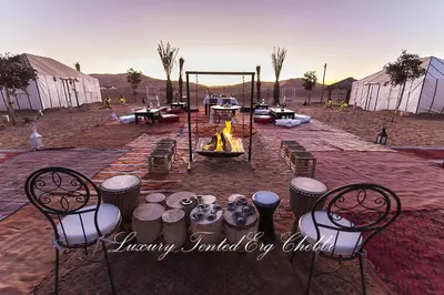 a group of chairs and a fire pit in a field at Luxury Tented Erg Chebbi in Merzouga