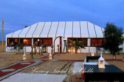 a white tent with tables and chairs in front of it at Luxury Tented Erg Chebbi in Merzouga