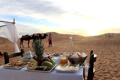 a table with food and a horse in the desert at Luxury Tented Erg Chebbi in Merzouga