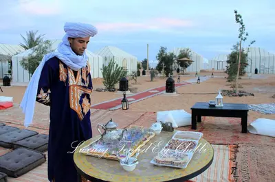 a man standing in front of a table with food on it at Luxury Tented Erg Chebbi in Merzouga