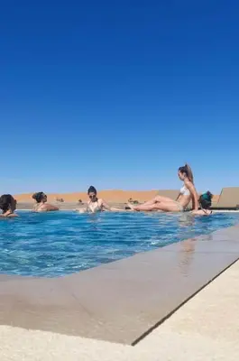 a group of people laying in a swimming pool at Riad Caravasar in Merzouga