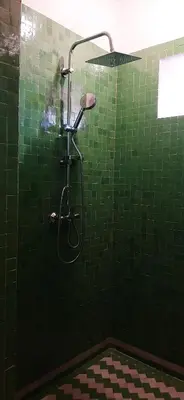 a green tiled shower in a green tile bathroom at Riad Caravasar in Merzouga