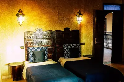 two beds in a room with yellow walls at Riad Caravasar in Merzouga
