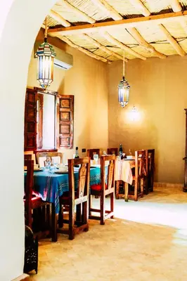 a dining room with a table and chairs and lights at Riad Caravasar in Merzouga