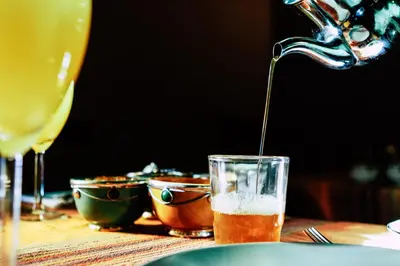 a drink is being poured into a glass on a table at Riad Caravasar in Merzouga