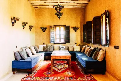 a living room with a blue couch and a table at Riad Caravasar in Merzouga