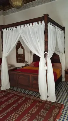 a bedroom with a canopy bed with white curtains at Dar Drissi in Fès