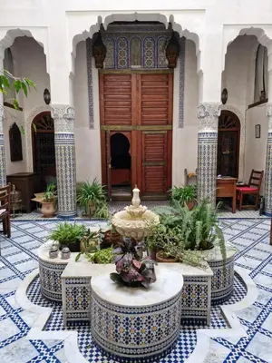 a courtyard with a fountain in front of a wooden door at Dar Drissi in Fès