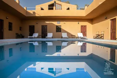 a swimming pool with chairs and a house at L'homme Du Désert A Merzouga in Merzouga