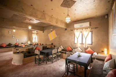 a restaurant with tables and chairs and a bar at L'homme Du Désert A Merzouga in Merzouga
