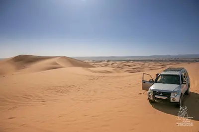 a white truck driving through the desert at L'homme Du Désert A Merzouga in Merzouga