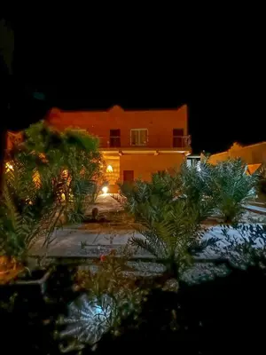 a building with a lot of plants in front of it at Dar Talmoudi ,Traditional Riad, Local Food, Camel , Desert Excursions in Tagounite