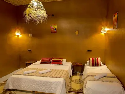 a bedroom with two beds and a chandelier at Dar Talmoudi ,Traditional Riad, Local Food, Camel , Desert Excursions in Tagounite