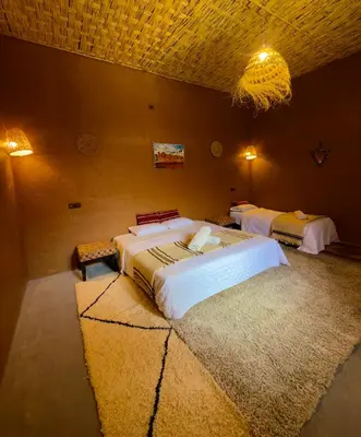 a bedroom with two beds in a room at Dar Talmoudi ,Traditional Riad, Local Food, Camel , Desert Excursions in Tagounite