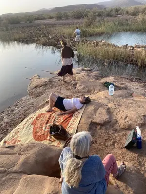 a group of people sitting on rocks near a body of water at Dar Talmoudi ,Traditional Riad, Local Food, Camel , Desert Excursions in Tagounite