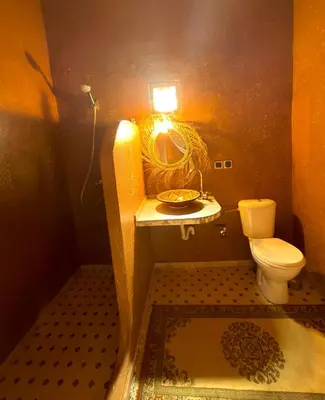 a bathroom with a toilet and a sink with a light at Dar Talmoudi ,Traditional Riad, Local Food, Camel , Desert Excursions in Tagounite