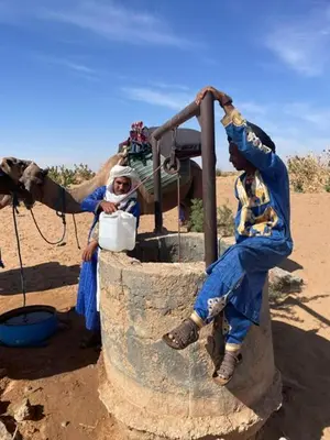 a couple of people sitting next to a water pump at Camp Desert Bivouac Chegaga in El Gouera