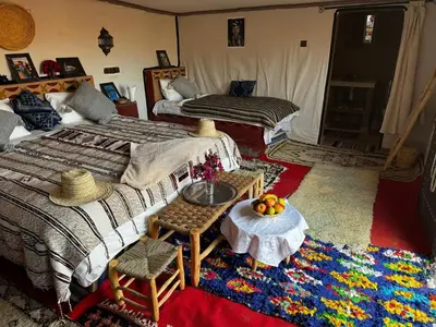 a bedroom with two beds and a table and chairs at Camp Desert Bivouac Chegaga in El Gouera