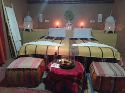 a bedroom with two beds with a bowl of fruit on a table at Desert Bivouac Mhamid in Mhamid