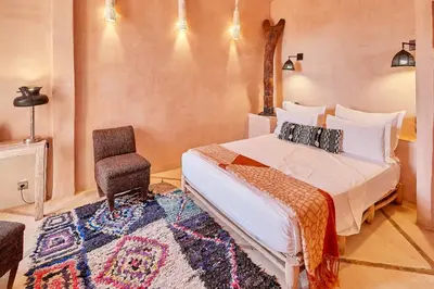 a bedroom with a bed and a chair at Riad Caravane in Aït Ben Haddou