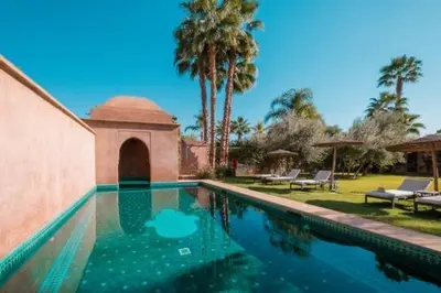 a swimming pool in a yard with palm trees at Villa Magtafa in Marrakech
